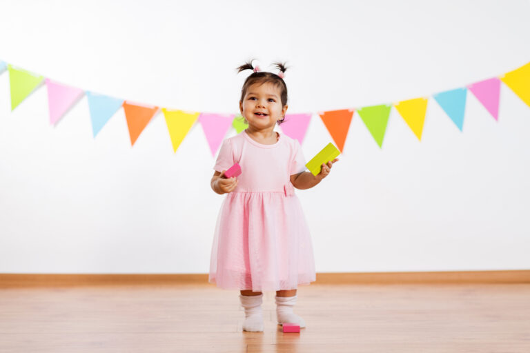 happy baby girl with toy blocks at birthday party