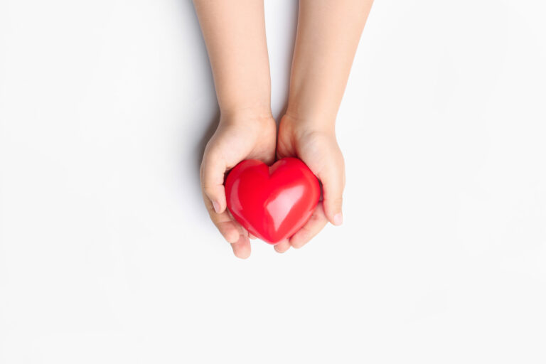 Child hands with red heart on white background