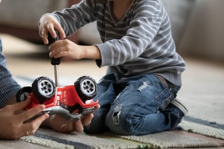 Happy father and little son playing with toy car together