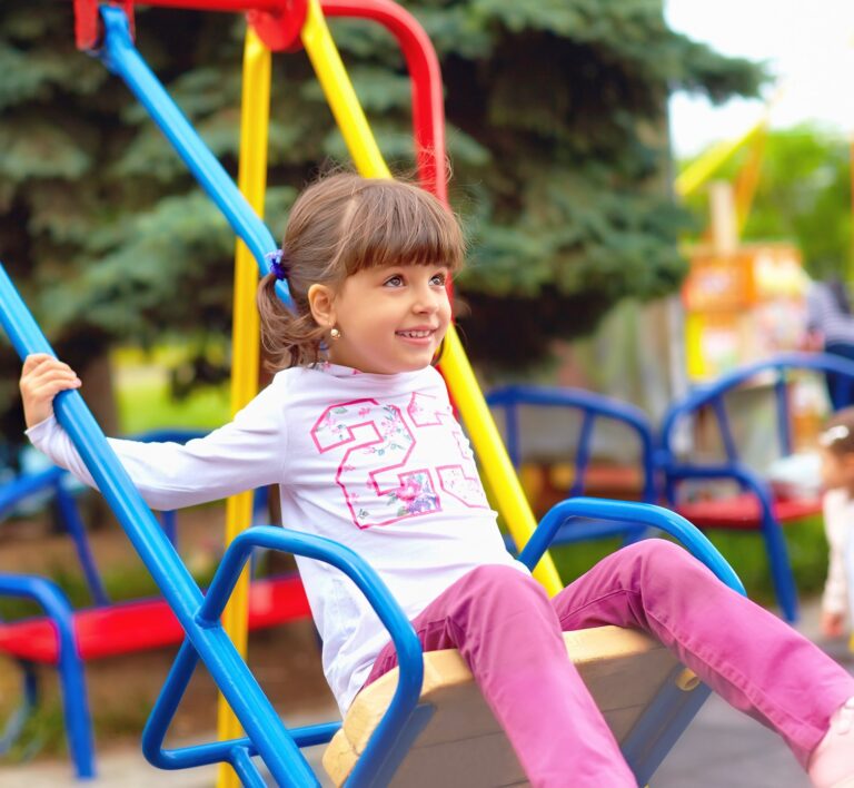 cute happy girl, kid having fun on swings at playground