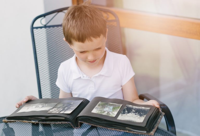 Little 7 years old boy browsing old photo album