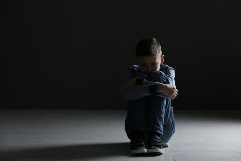 Upset boy sitting in dark room